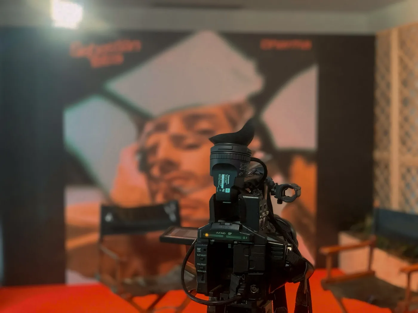 Set de producción audiovisual con cámara profesional, fondo gráfico, sillas de dirección e iluminación para grabación de contenido de marca