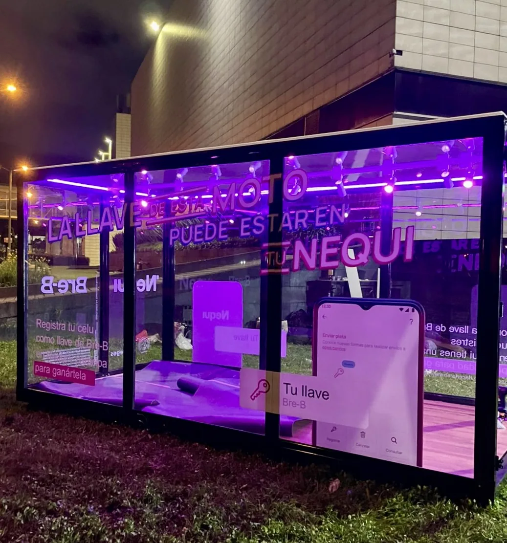 Vitrina itinerante de Nequi con estructura en vidrio, iluminación interior, motocicleta exhibida y gráfica promocional para activación de marca