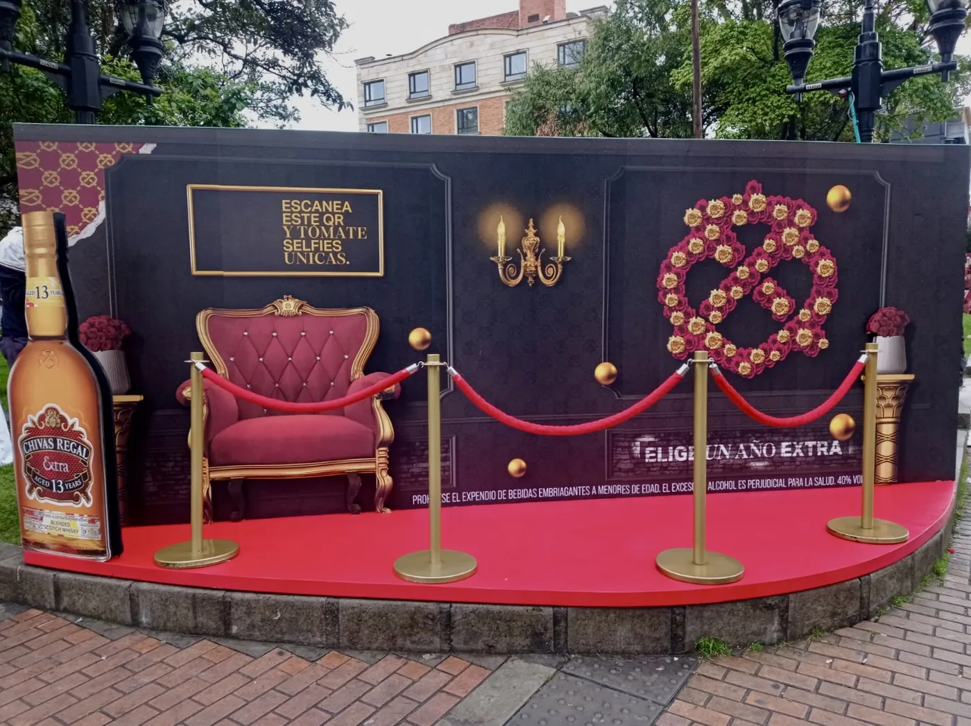 Set BTL de Chivas Regal con backing escenográfico, sofá rojo, botella de gran formato, cuerda de acceso y espacio para selfies de marca