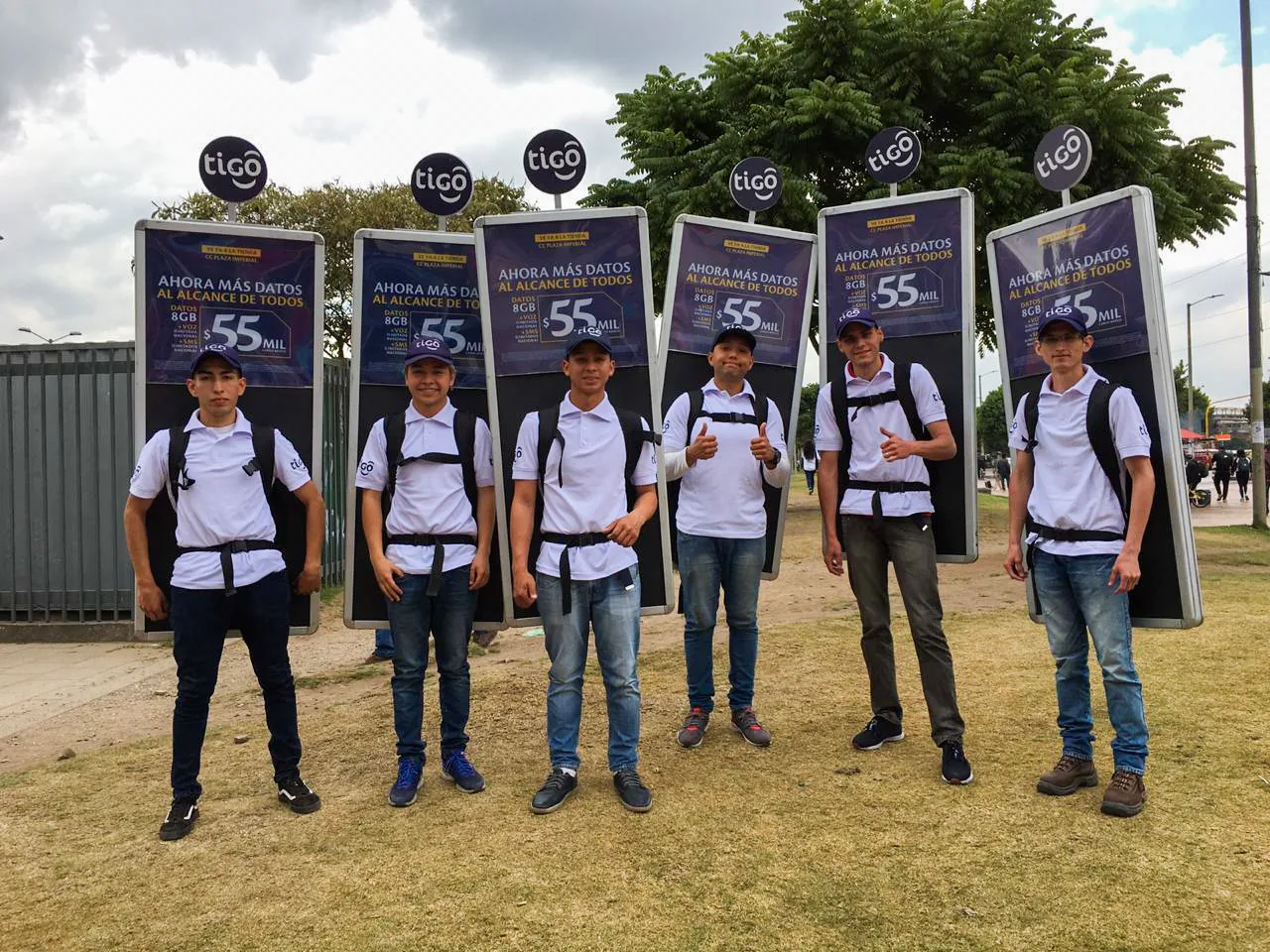 Promotores con mochilas publicitarias tipo backpack de Tigo para activación BTL en espacio exterior de alto tráfico