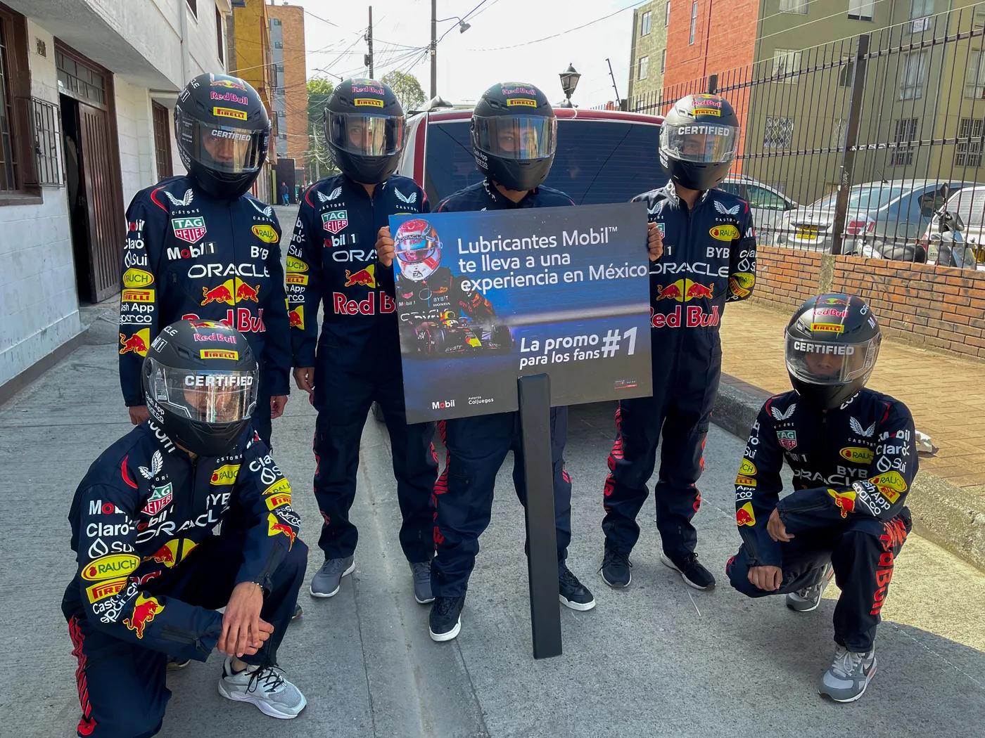 Promotores con trajes de piloto Red Bull para campaña Mobil, sosteniendo señalización promocional de experiencia de marca