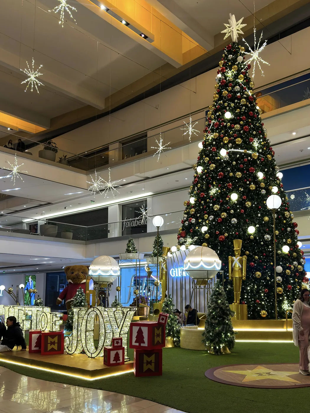 Árbol de Navidad comercial instalado en centro comercial Multiplaza con base escenográfica roja, esferas decorativas e iluminación de temporada
