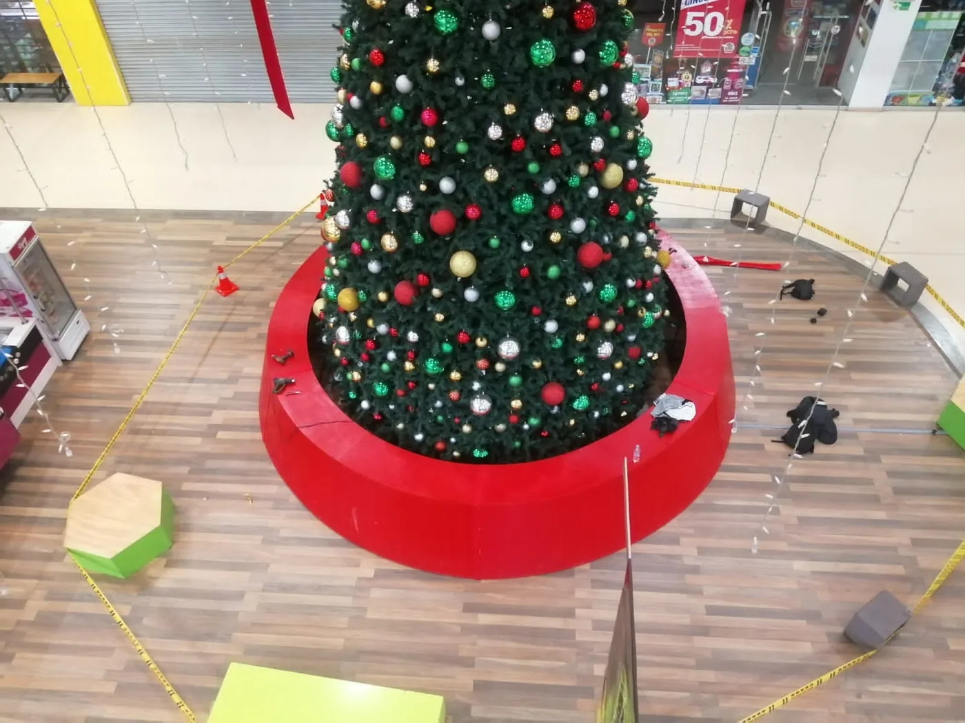 Base circular roja instalada alrededor de árbol de Navidad comercial en centro comercial durante proceso de montaje y ambientación de temporada