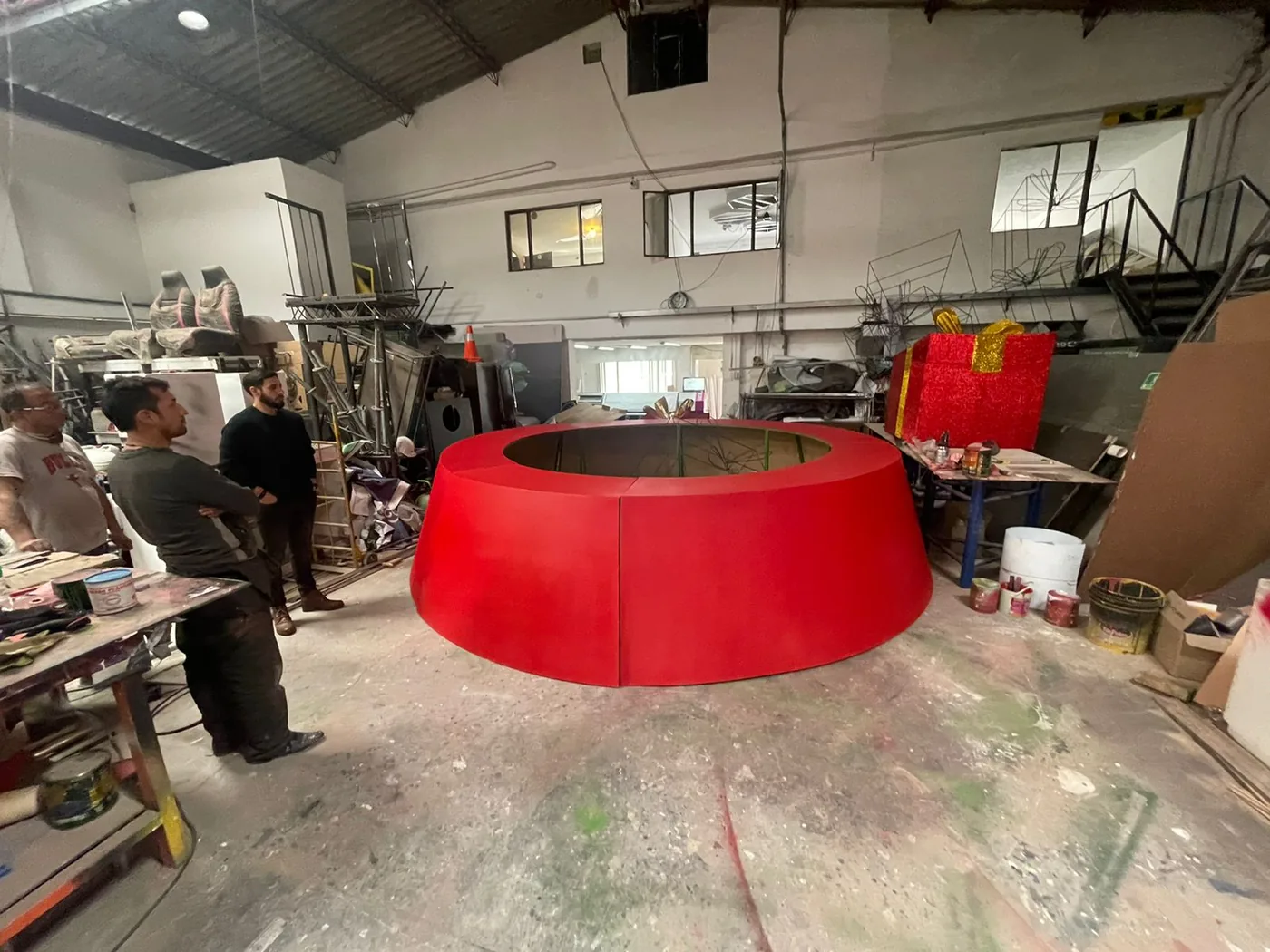 Proceso de fabricación en taller de base circular roja para árbol de Navidad de gran formato, con estructura escenográfica en producción