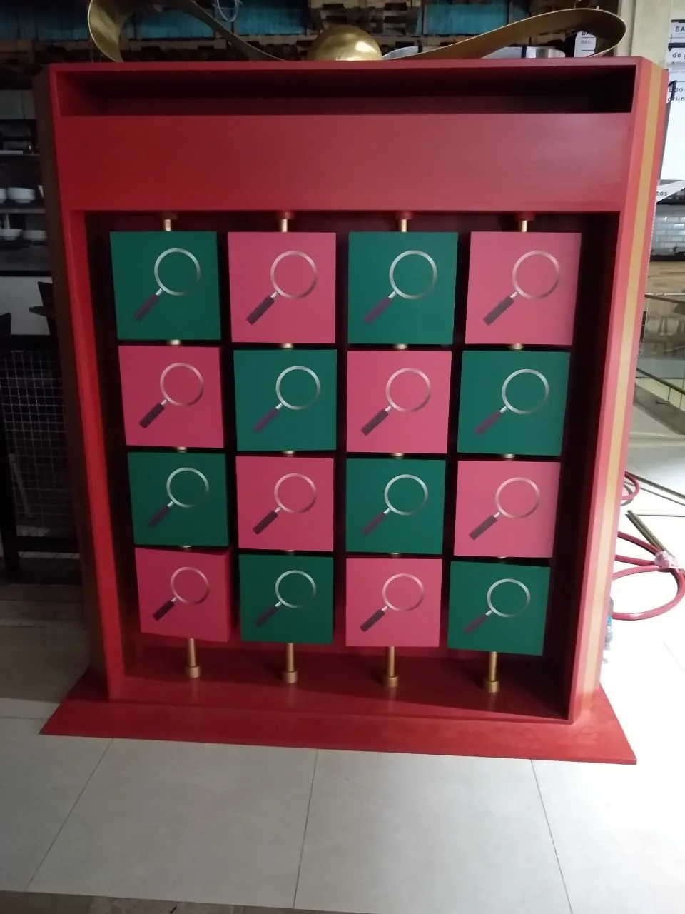 Módulo interactivo navideño con estructura roja, paneles giratorios en verde y rosado, y gráfica de lupa para dinámica comercial de temporada