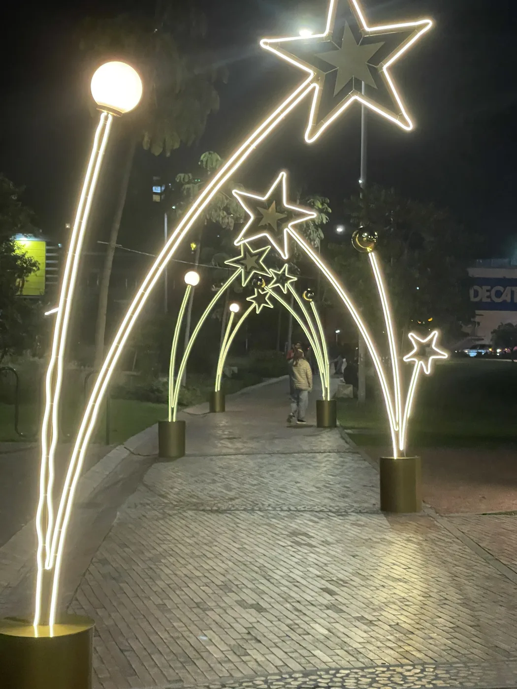 Sendero peatonal decorado con figuras navideñas en forma de estrella e iluminación ornamental para ambientación de temporada