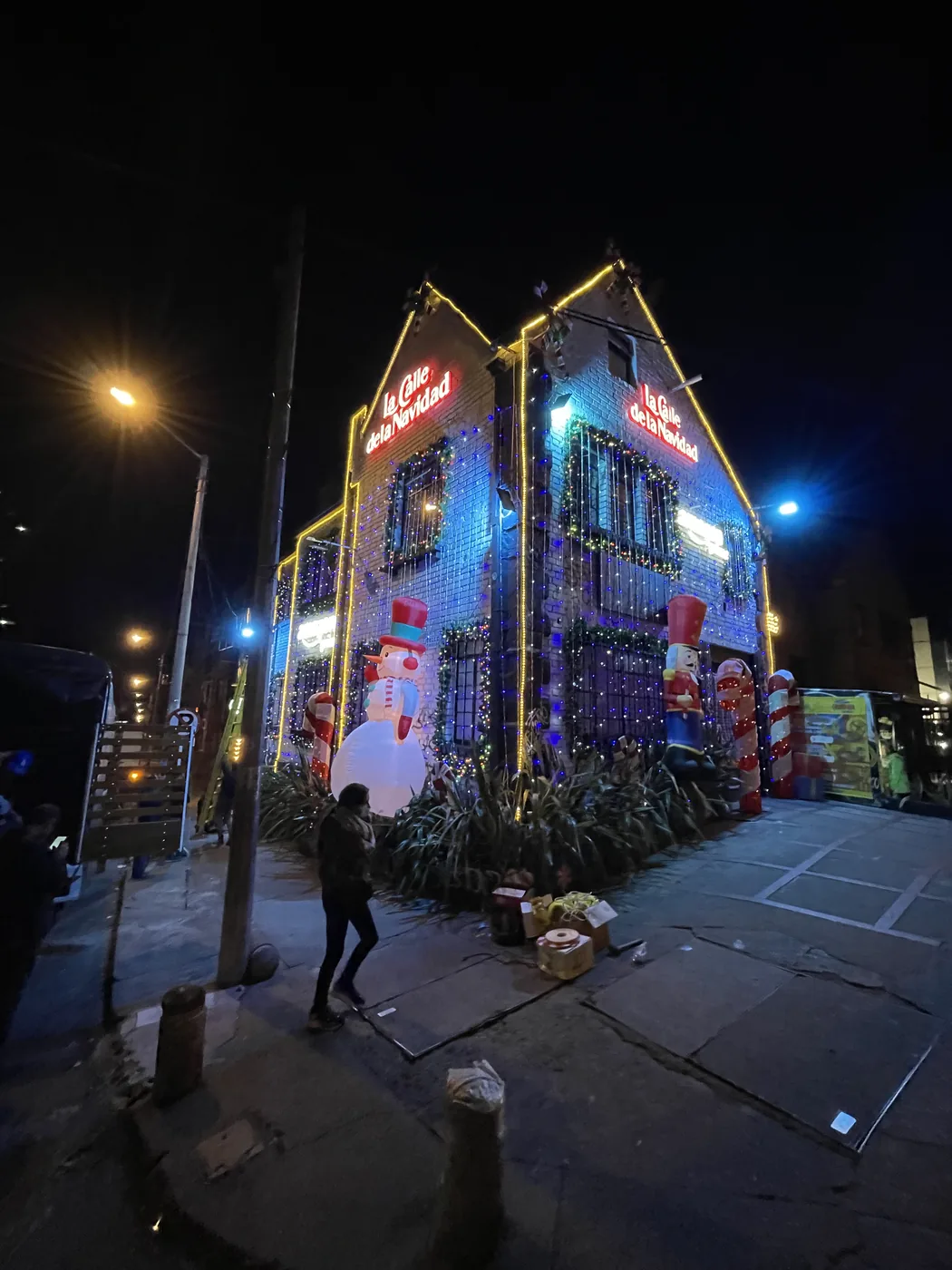 Casa esquinera escenográfica con decoración navideña, acabados temáticos e iluminación para montaje comercial de temporada