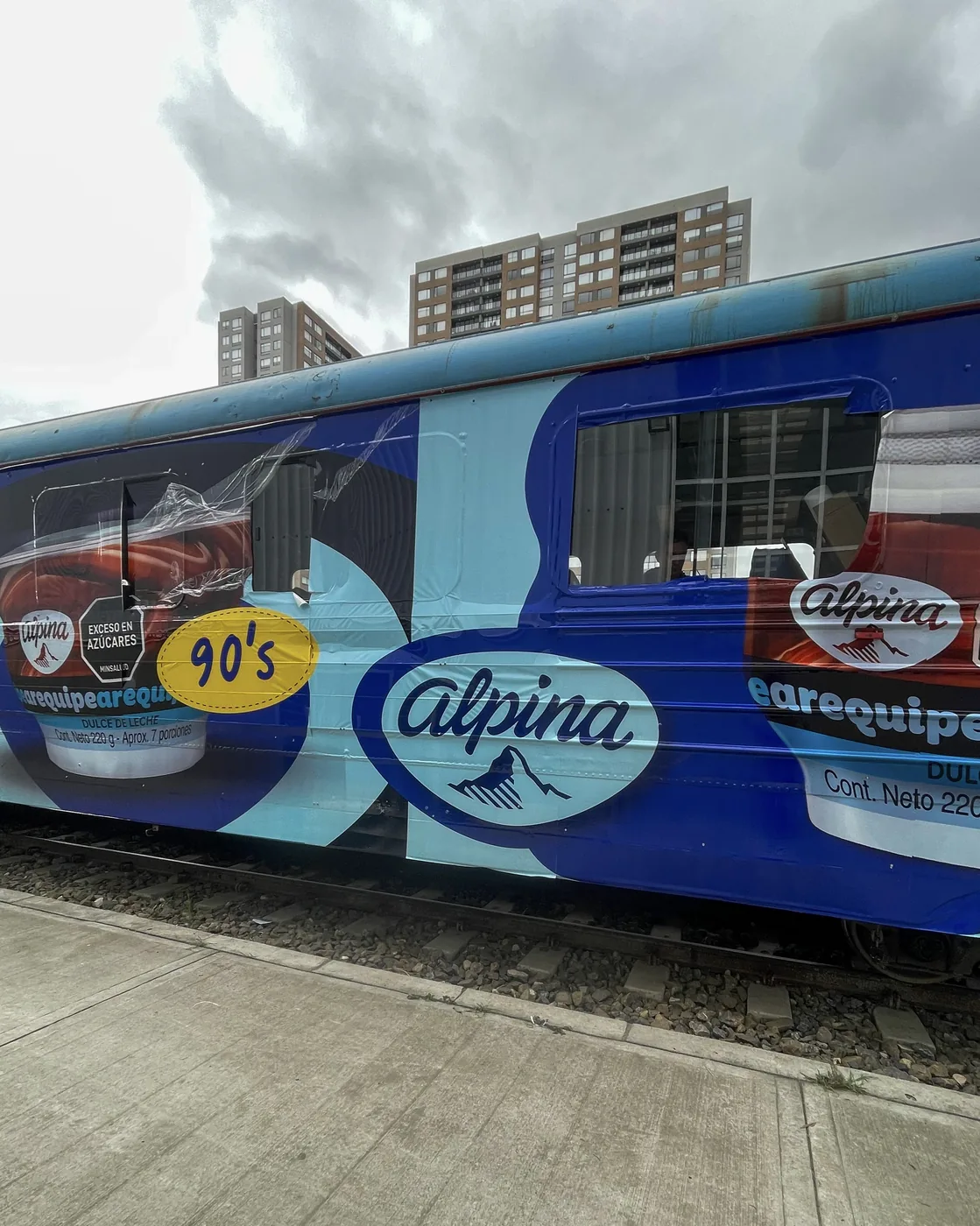 Tren comercial completamente brandeado con gráfica publicitaria de gran formato aplicada sobre vagones para campaña OOH de alto impacto