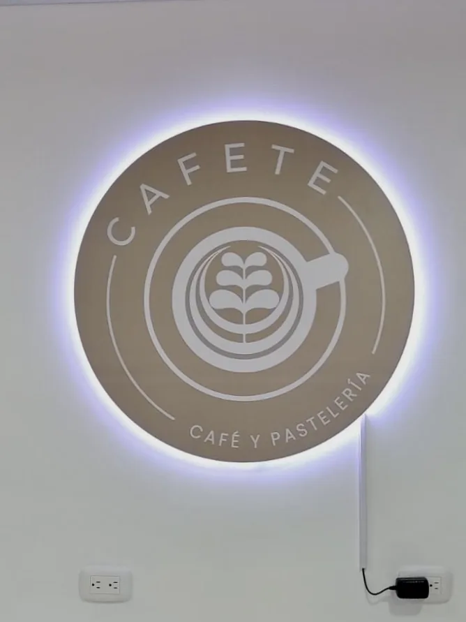 Aviso luminoso circular para café instalado sobre muro interior con iluminación perimetral y diseño de marca elegante