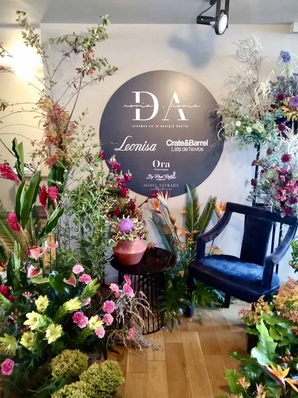 Decoración floral para marca comercial con composición vegetal, flores de colores y elemento gráfico central para punto de venta