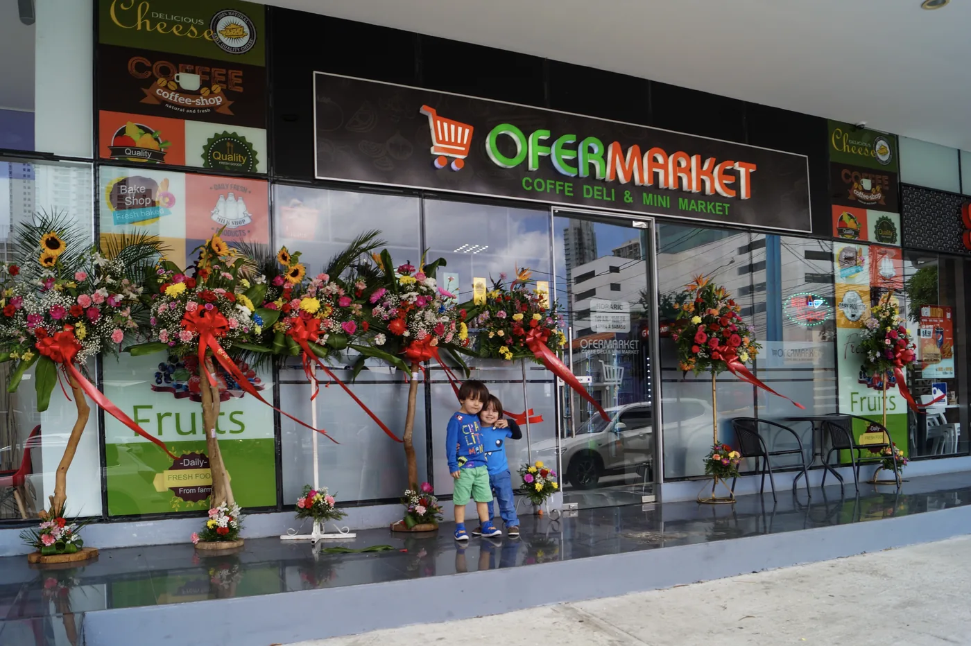 Decoración comercial para fachada de supermercado con arreglos florales, elementos ornamentales y ambientación visual para punto de venta