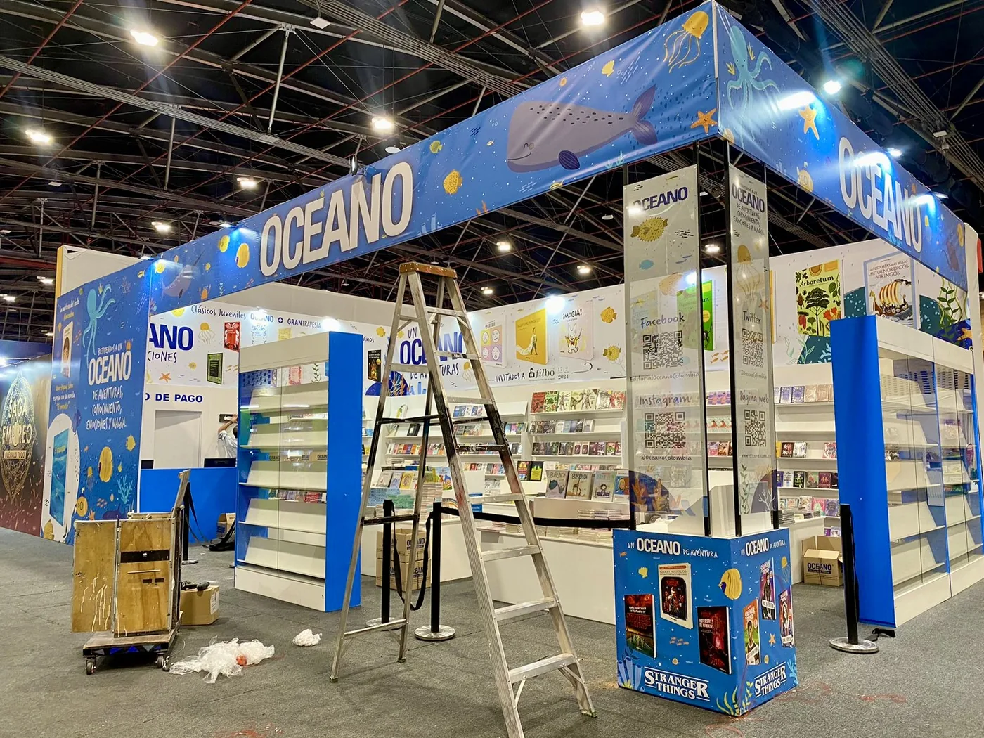 Stand ferial de la marca Oceano con estructura azul, exhibición de libros y diseño modular para exposición comercial