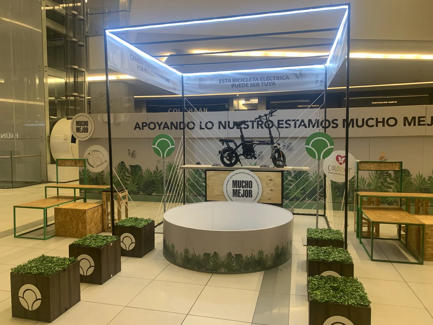 Activación de marca en centro comercial con escenografía iluminada, estructura metálica, mobiliario y elementos decorativos en torno a una experiencia de producto