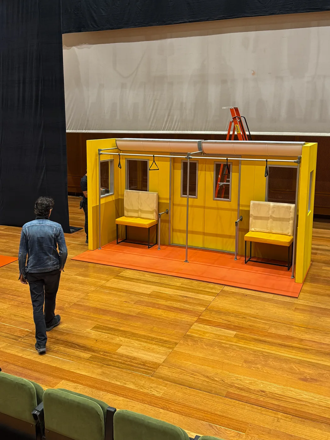 Set escenográfico con apariencia de fachada arquitectónica en color amarillo, instalado en escenario interior para experiencia o grabación
